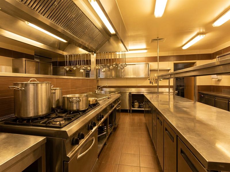 Cozinha industrial equipada com fogão e bancadas de aço inox